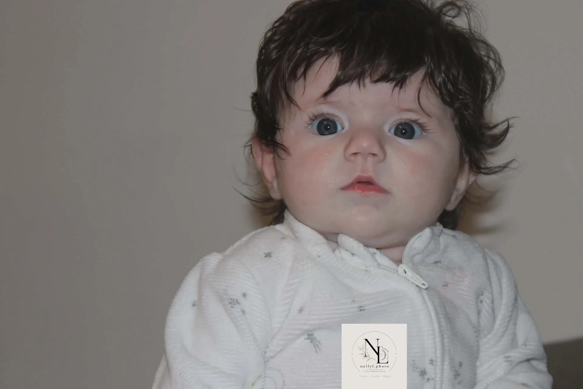 Bébé en grenouillère blanche, regard ouvert vers l’objectif